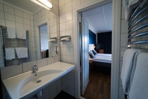 a bathroom with a sink and a mirror and a bed at Hotel Gyllene Uttern in Gränna
