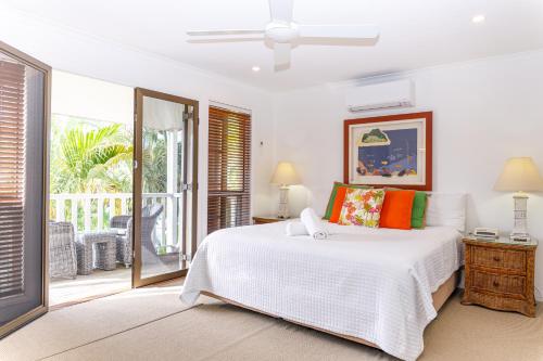 a white bedroom with a bed and a balcony at Sandy Beach Resort in Noosaville