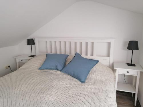 ein weißes Bett mit zwei blauen Kissen darauf in der Unterkunft Townhouse Altstadt Wismar Upper Apartment mit zwei Terrassen in Wismar