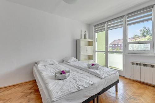 a white bedroom with a large bed and a large window at Wave Apartments - ŻUŁAWIANKA GDAŃSK in Gdańsk