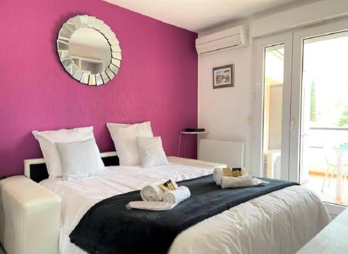 - une chambre avec un grand lit et un mur pourpre dans l'établissement Appartement Imperia St Raphaël, au calme, vue piscine, climatisé, à Saint-Raphaël