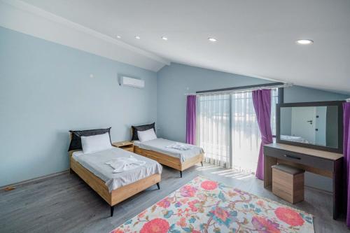 a bedroom with two beds and a flat screen tv at Villa Ada in Fethiye