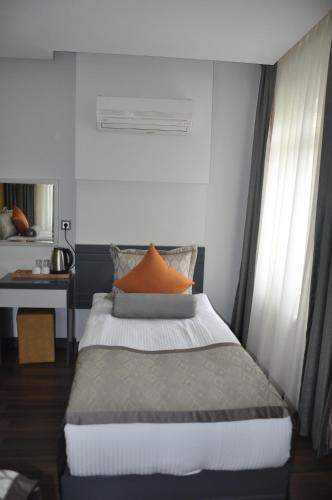 a bedroom with a bed with an orange pillow on it at KOÇ OTEL ELİT TERMİNAL in Isparta