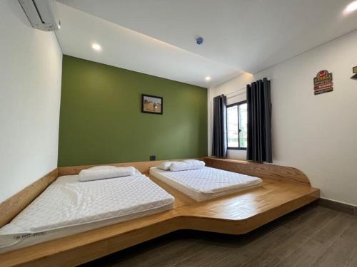 two beds in a room with a green wall at Tom Homestay Quy Nhơn in Quy Nhon