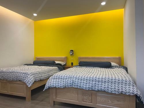 two beds in a room with a yellow wall at Tom Homestay Quy Nhơn in Quy Nhon