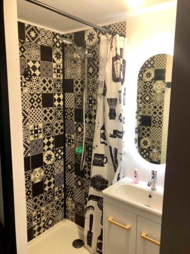 La salle de bains est pourvue d'un rideau de douche noir et blanc et d'un lavabo. dans l'établissement Maison charmante avec piscine privée à Saint-Georges-de-PointindouxC, à Saint-Georges-de-Pointindoux