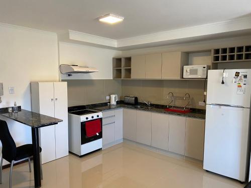 eine Küche mit weißen Geräten und einem Tisch darin in der Unterkunft Departamento con vistas al lago en Veneto Village in Villa Parque Siquiman