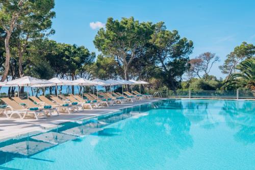 einen Pool mit Liegestühlen und Sonnenschirmen in der Unterkunft Iberostar Club Cala Barca All Inclusive in Portopetro