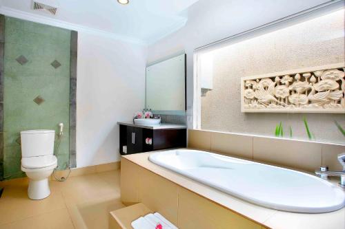 a bathroom with a tub and a toilet and a sink at Legian Family villa with pool in Legian