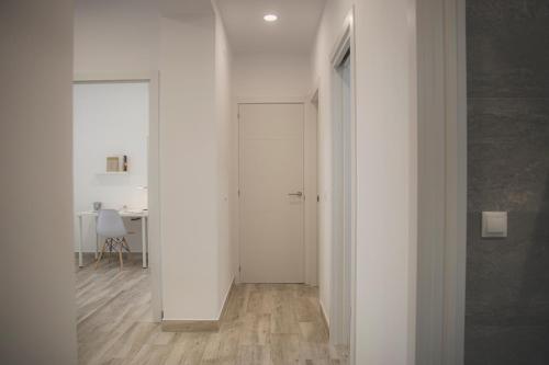 einen Flur mit weißen Wänden und einer weißen Tür in der Unterkunft Acogedor apartamento en Triana in Sevilla