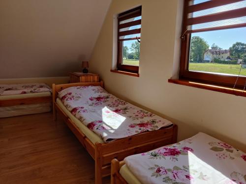 two twin beds in a room with a window at Domek z Klimatem in Smołdziński Las