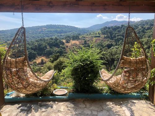 two hammocks hanging from a porch with a view of the mountains at Yogaville Sardegna in Luras