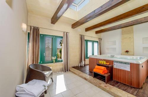 ein großes Bad mit einer Badewanne und einem Stuhl in der Unterkunft Djar ta Menzja 2 Holiday Home in Sannat