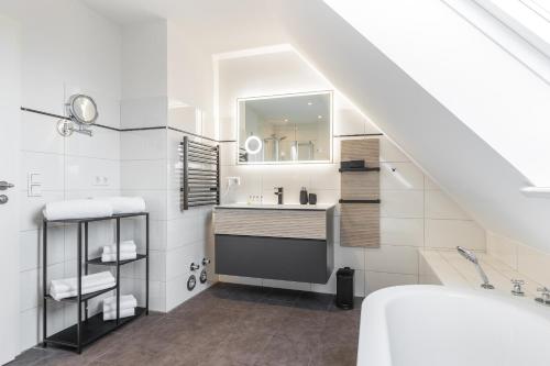 a white bathroom with a sink and a mirror at Appartement Friesenloft in Tinnum