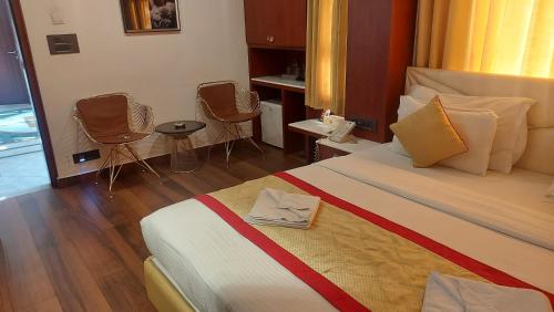 a hotel room with a large bed and chairs at Hotel Manila in Siliguri