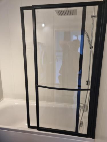 La salle de bains est pourvue d'une douche avec une porte en verre. dans l'établissement Bel appartement 2 chambres ,résidence privée, à Givet