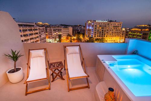 a balcony with two chairs and a bath tub at The Suite Athens in Athens