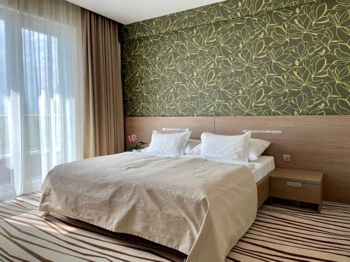 ein Schlafzimmer mit einem großen Bett und einer grünen Wand in der Unterkunft Hotel Ponteo - Activity Park in Bratislava