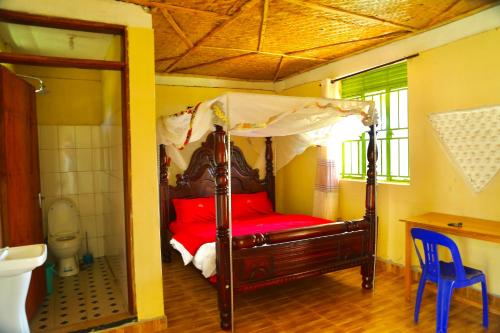 a bedroom with a canopy bed and a toilet at Sina Village in Mpigi