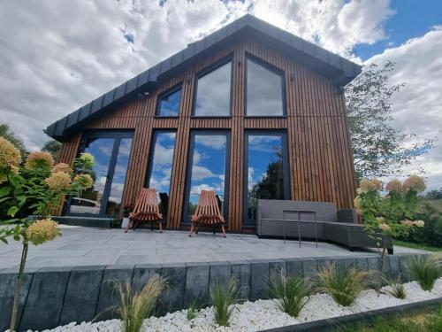 ein Holzhaus mit zwei Stühlen davor in der Unterkunft Wy_spa_Podolany in Gdów