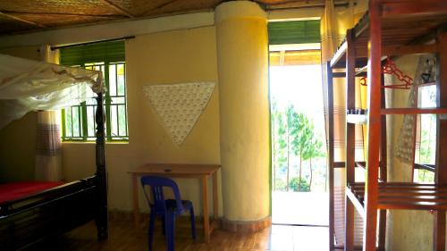 a bedroom with a bed and a table and a window at Sina Village in Mpigi