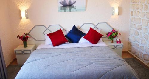 Kaouki beach Apart'hotel في سيدي كاوكي: غرفة نوم مع سرير مع الوسائد الحمراء والزرقاء