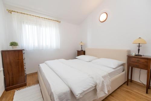 a white bedroom with a large bed and a window at Apartments Villa Castello in Crikvenica