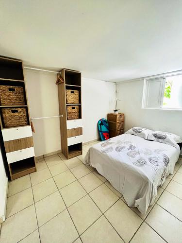 een slaapkamer met een bed en een tegelvloer bij Appartement de 2 chambres avec jardin et wifi a Petit Bourg in Petit-Bourg