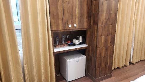 a corner of a room with curtains and a small refrigerator at Hotel Manila in Siliguri