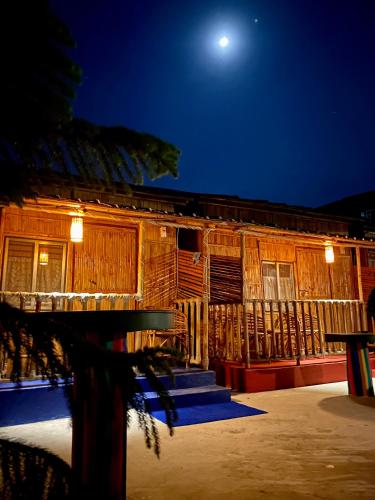 a wooden building at night with a full moon at Tridhara HomeStay in Guwahati
