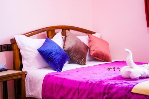 a bed with colorful pillows and a white duck on it at Hotel EL MARSA LA PLAYA in Laayoune
