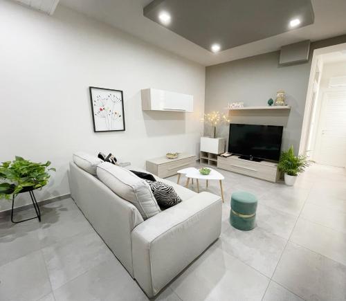 uma sala de estar branca com um sofá e uma televisão em Casa Lulu em Belpasso