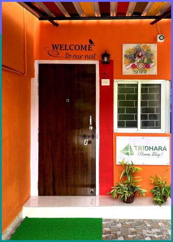 an orange building with a welcome to our next door at Tridhara HomeStay in Guwahati