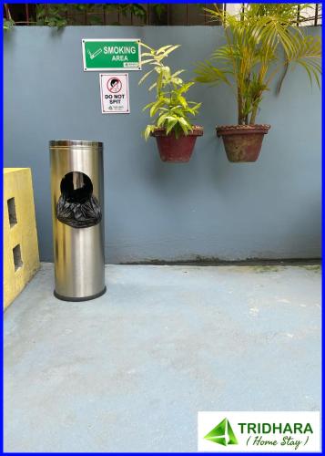 a trash can sitting next to a wall with plants at Tridhara HomeStay in Guwahati