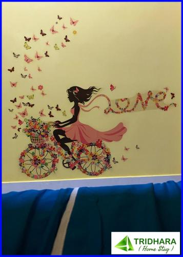 a girl on a bicycle with butterflies and flowers vinyl wall art at Tridhara HomeStay in Guwahati