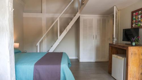 a bedroom with a bed and a tv and stairs at Pousada Tartaruga in Búzios