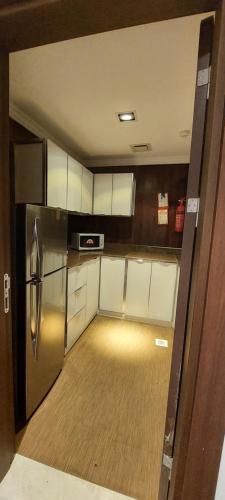 uma pequena cozinha com frigorífico e armários brancos em EMAN HOUSE em Salalah