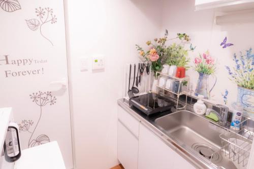 una cucina con lavandino e fiori sul muro di Jellynehouse新大久保 a Tokyo