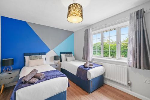 two beds in a room with blue walls and windows at Waterside House - Free Parking in Hoo
