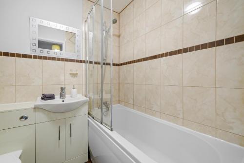 La salle de bains est pourvue d'une baignoire, d'un lavabo et d'une douche. dans l'établissement Waterside House - Free Parking, à Hoo