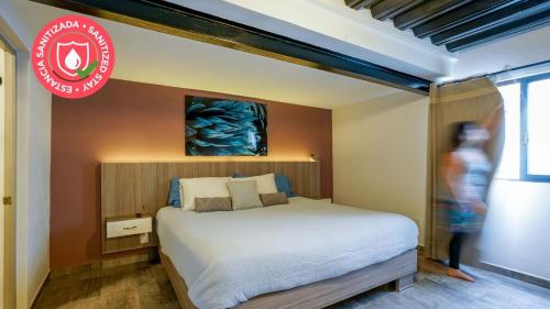 a bedroom with a bed and a person walking in front of it at Casa Carmelia La Condesa in Mexico City