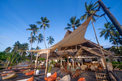 a restaurant on the beach with palm trees at Villa Kiva Boutique Hotel in Matemwe