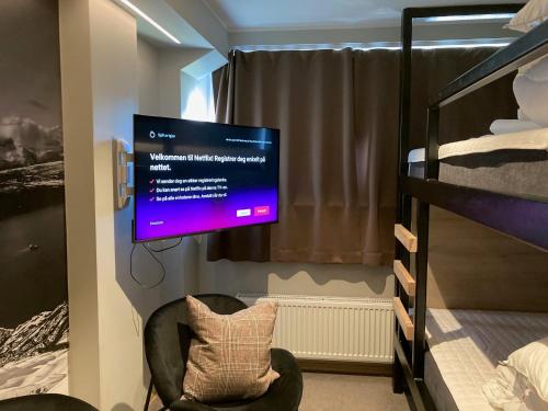 a room with a tv and a chair and bunk beds at Breidablikk Guesthouse in Narvik