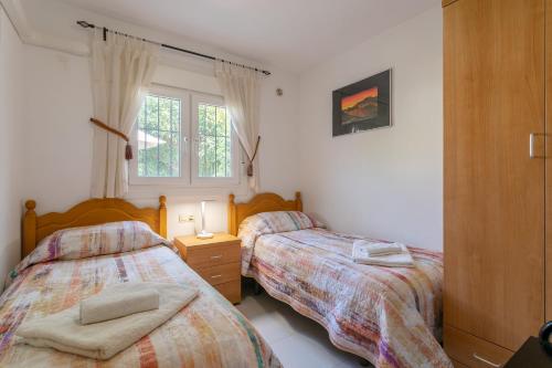 1 dormitorio con 2 camas y ventana en Heads 2 Holiday Homes Apartment, en Villamartin