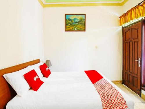 um quarto com uma cama com almofadas vermelhas e brancas em OYO 91564 Ayodya Guest House em Mataram