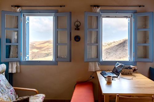 a room with two windows and a desk with a laptop at Villa Nina, dreamy little cycladic home in Amorgos in Órmos Aiyialís