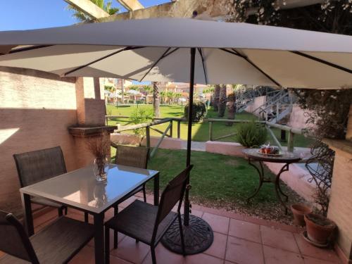 een tafel en stoelen met een parasol op een patio bij Beach-Golf House in Islantilla