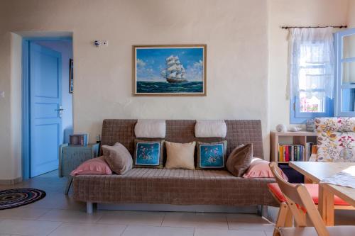 een woonkamer met een bank en een schilderij van een schip bij Villa Nina, dreamy little cycladic home in Amorgos in Órmos Aiyialís