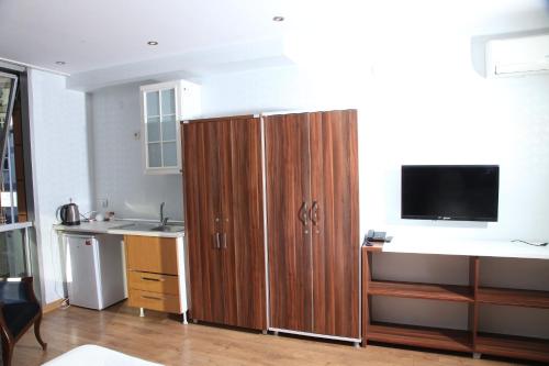 cocina con un gran armario de madera y TV de pantalla plana en GARDEN HILL HOTEL, en Estambul