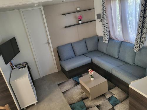 a living room with a blue couch and a tv at Mobil-home L'Olivier in Fréjus